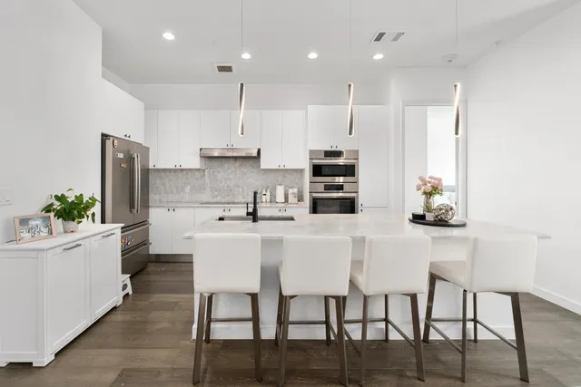 a kitchen with stainless steel appliances kitchen island granite countertop a table chairs sink and cabinets