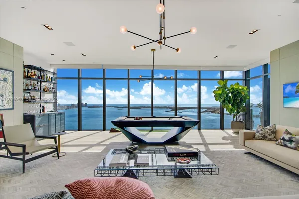 a living room with furniture a chandelier and a floor to ceiling window