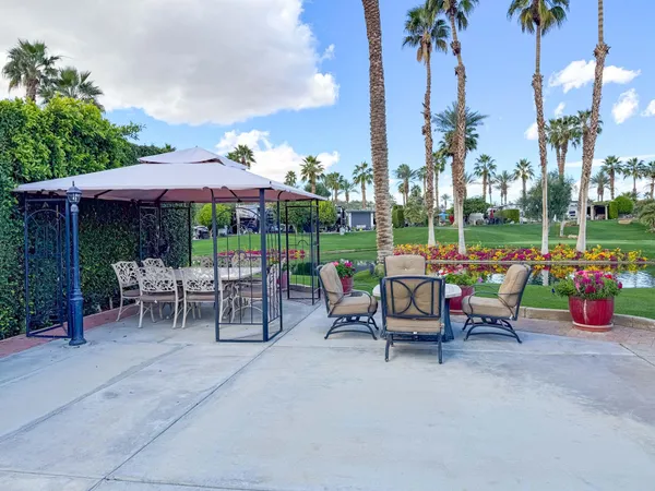 a view of a patio with a table and chairs under an umbrella with palm trees