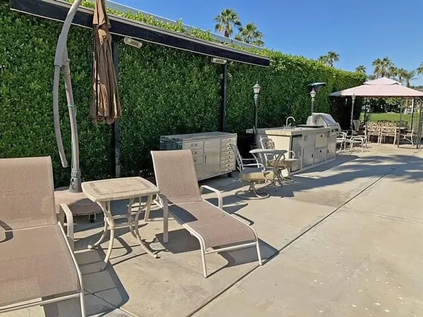 a view of a patio with a dining table and chairs under an umbrella with a small yard