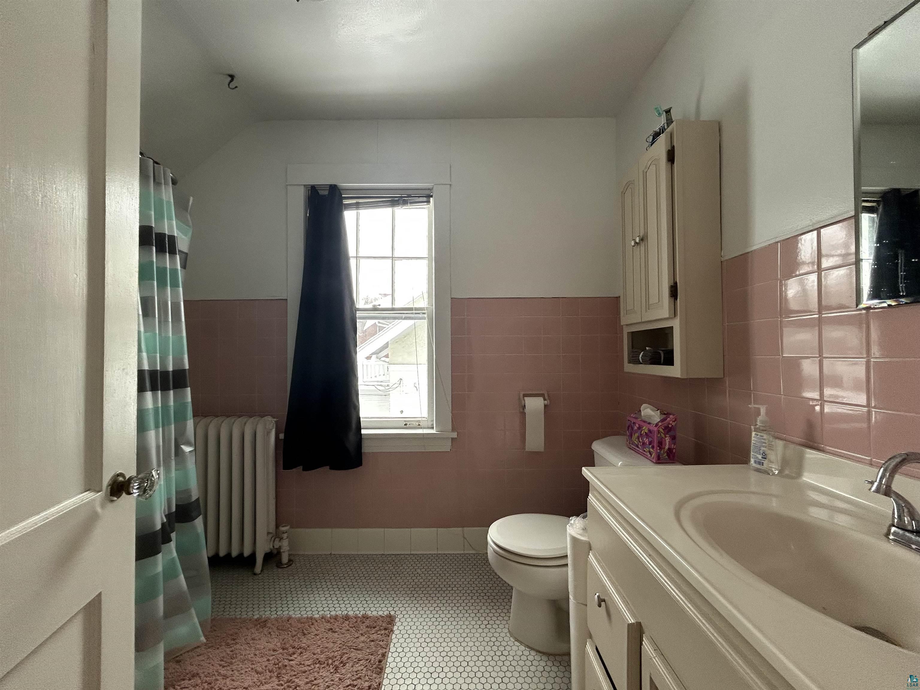1723 East 4th Street Duluth, MN 55812 - Photo 27 of 47 Full bath with vanity, wainscoting, radiator heating unit, curtained shower, and tile walls