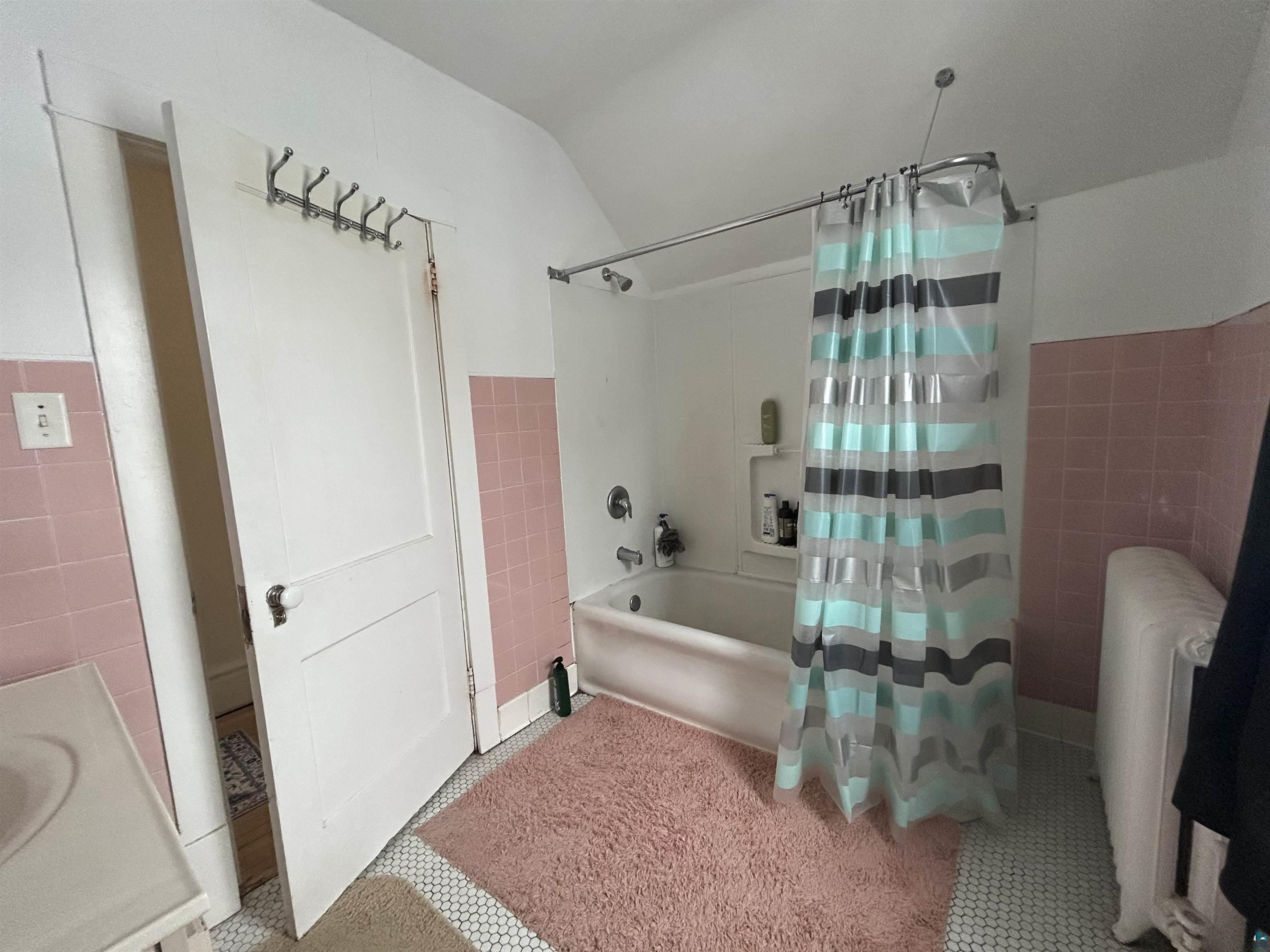 1723 East 4th Street Duluth, MN 55812 - Photo 28 of 47 Full bath featuring tile walls, shower / tub combo with curtain, wainscoting, radiator heating unit, and vanity