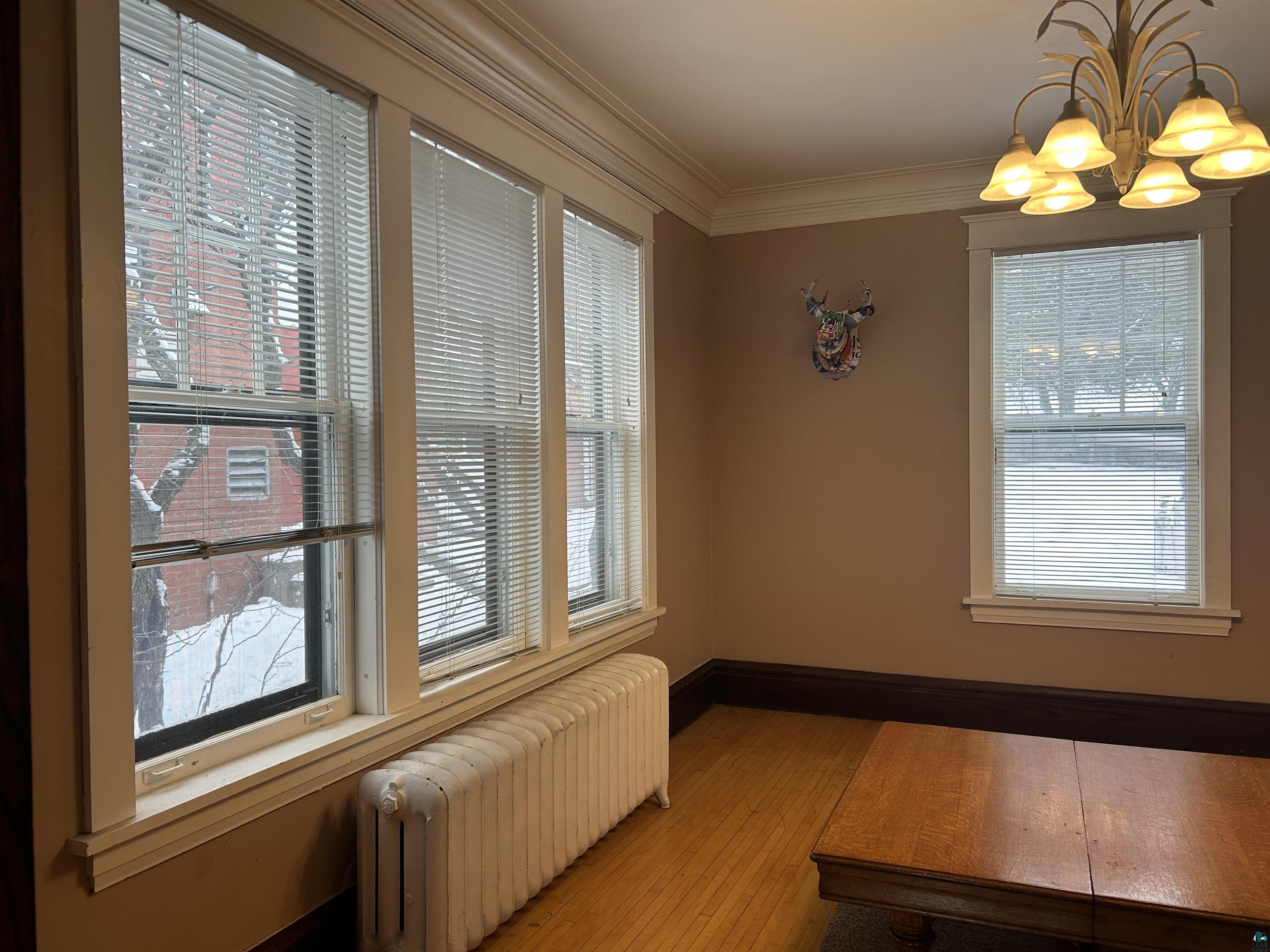 1723 East 4th Street Duluth, MN 55812 - Photo 33 of 47 Dining space featuring radiator, a chandelier, ornamental molding, and hardwood / wood-style flooring