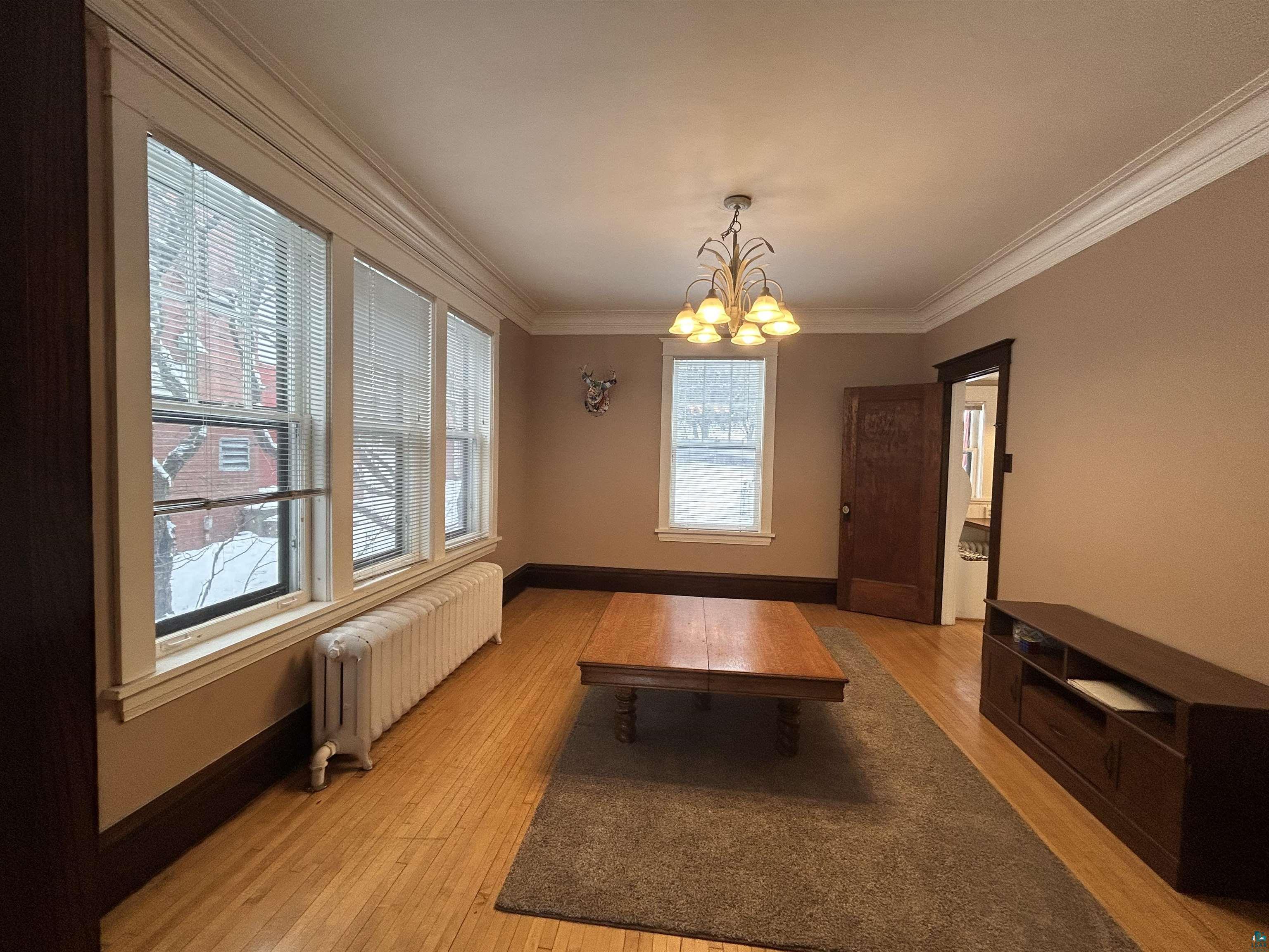 1723 East 4th Street Duluth, MN 55812 - Photo 34 of 47 Unfurnished dining area featuring radiator heating unit, a chandelier, light wood finished floors, and ornamental molding