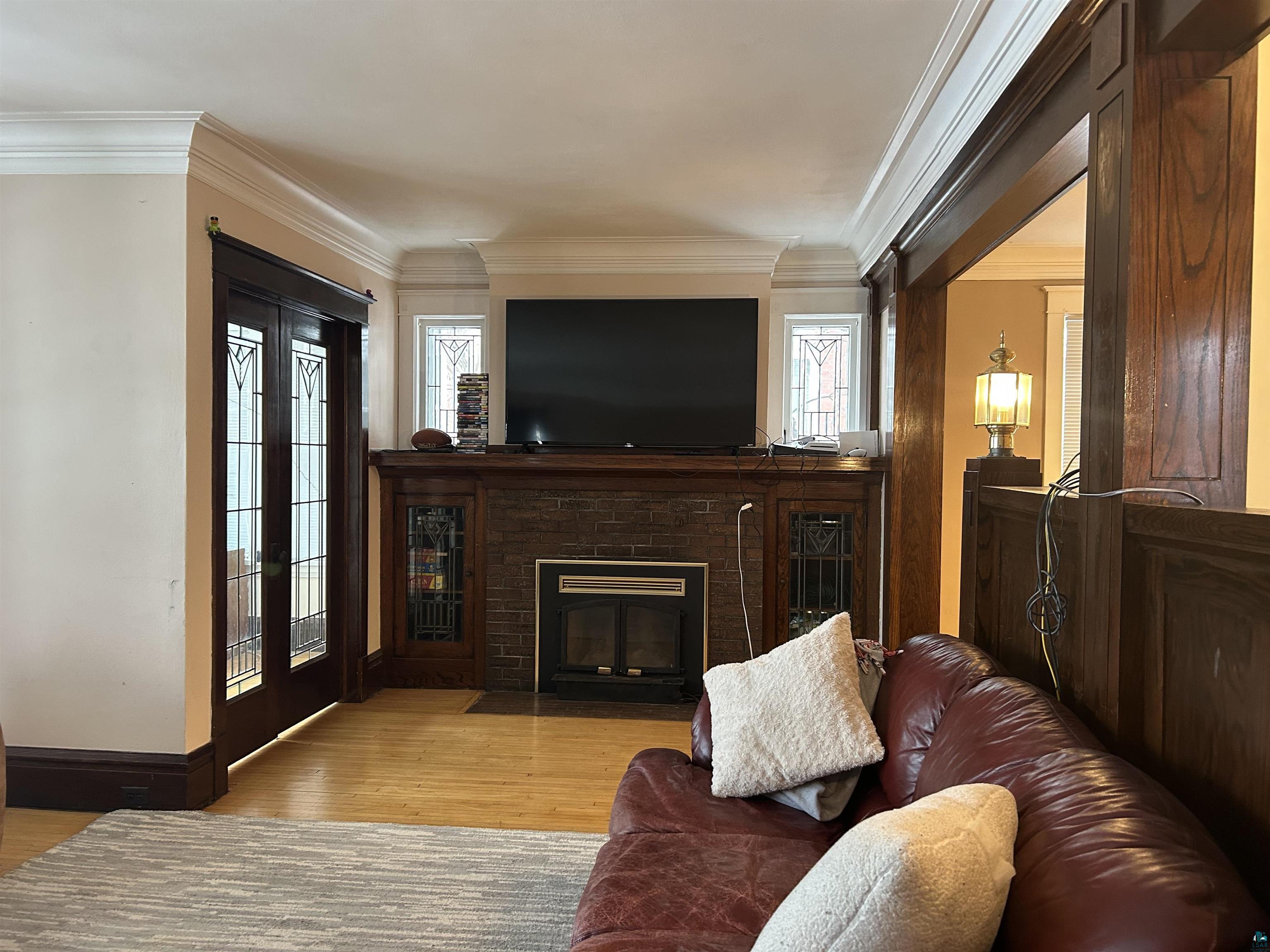 1723 East 4th Street Duluth, MN 55812 - Photo 47 of 47 Living area with light wood-style flooring, crown molding, and a brick fireplace