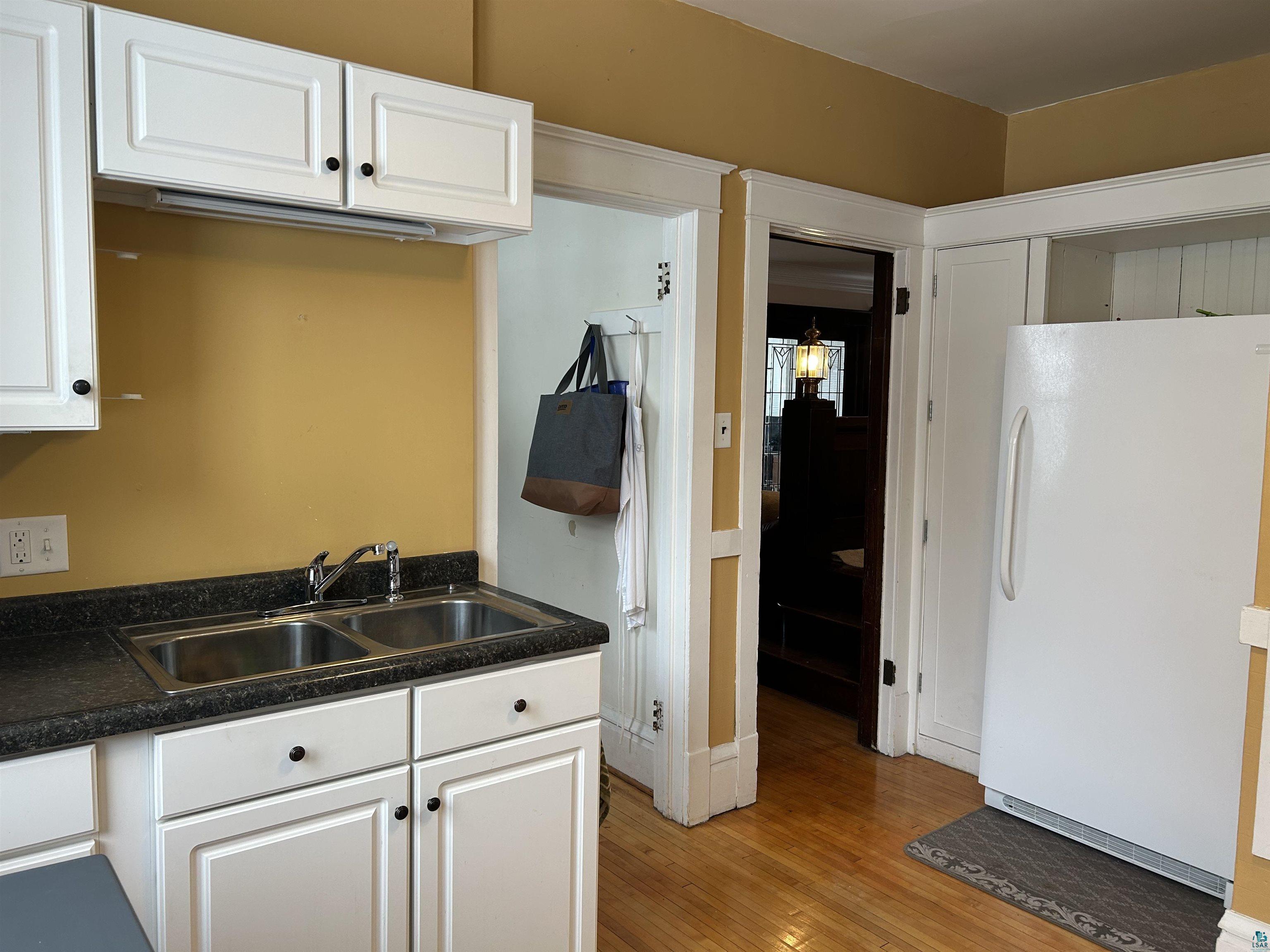1723 East 4th Street Duluth, MN 55812 - Photo 8 of 47 Kitchen with white cabinetry, freestanding refrigerator, dark countertops, and light wood-style flooring