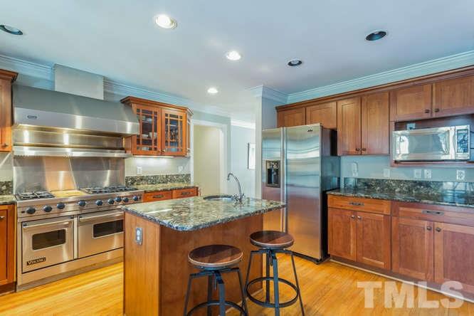 906 Runnymede Road Raleigh, NC 27607 - Photo 13 of 25 a kitchen with stainless steel appliances granite countertop a stove top oven a sink and a refrigerator