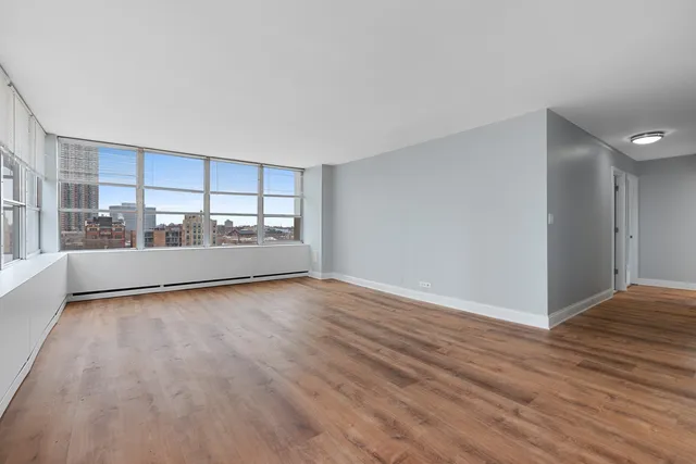 a view of an empty room with a window and wooden floor