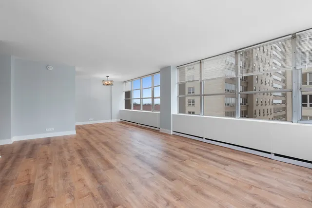 a view of an empty room with a window and wooden floor