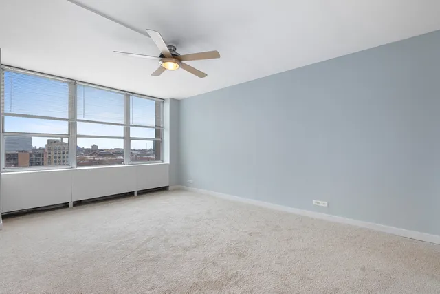 an empty room with a ceiling fan and window