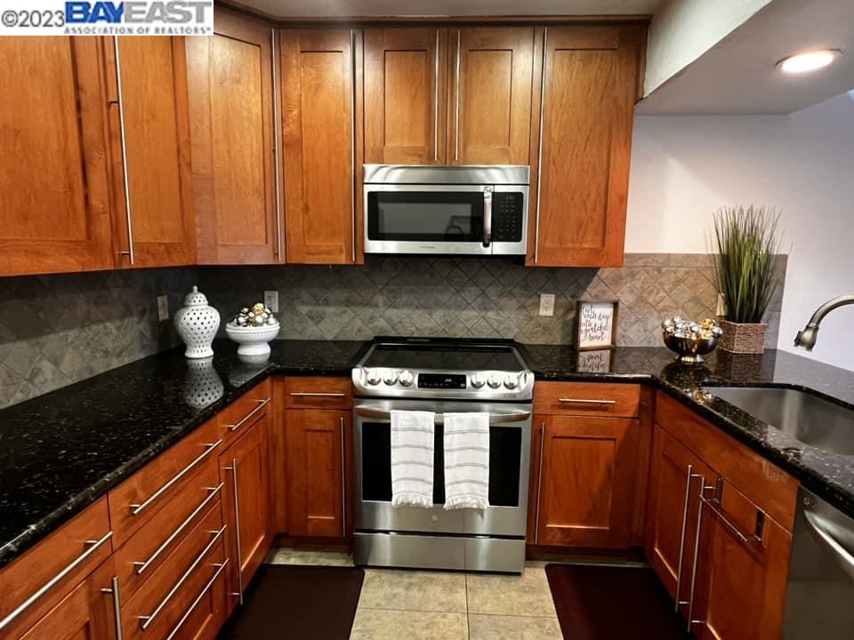 a kitchen with stainless steel appliances granite countertop wooden cabinets a sink and a counter space