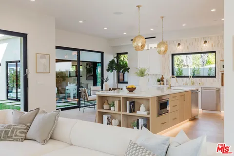 a living room with furniture kitchen view and a large window