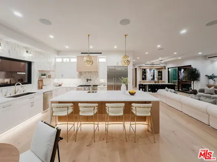 a large white kitchen with a large counter top furniture and appliances