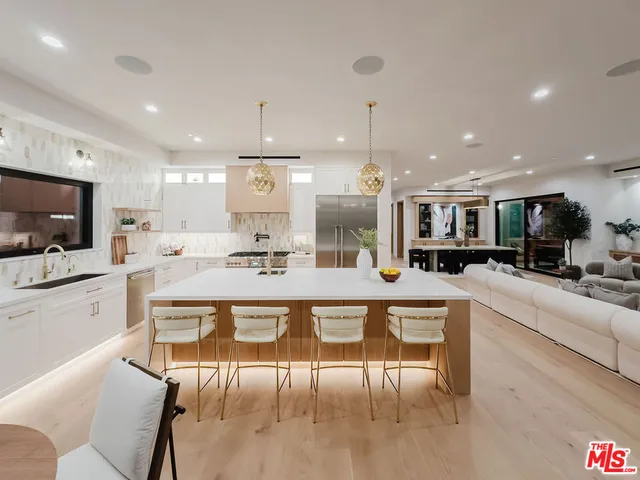 a large white kitchen with a large counter top furniture and appliances