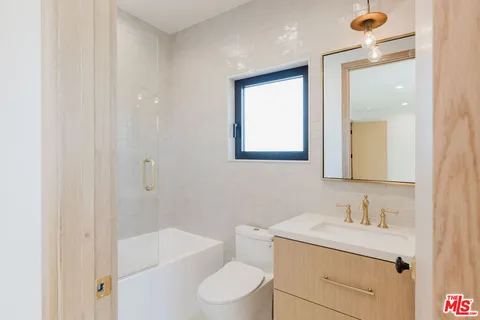 a bathroom with a granite countertop sink toilet a mirror and shower