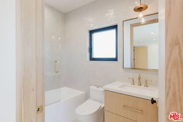 a bathroom with a granite countertop sink toilet a mirror and shower