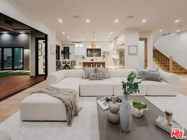 a living room with furniture potted plant and kitchen view