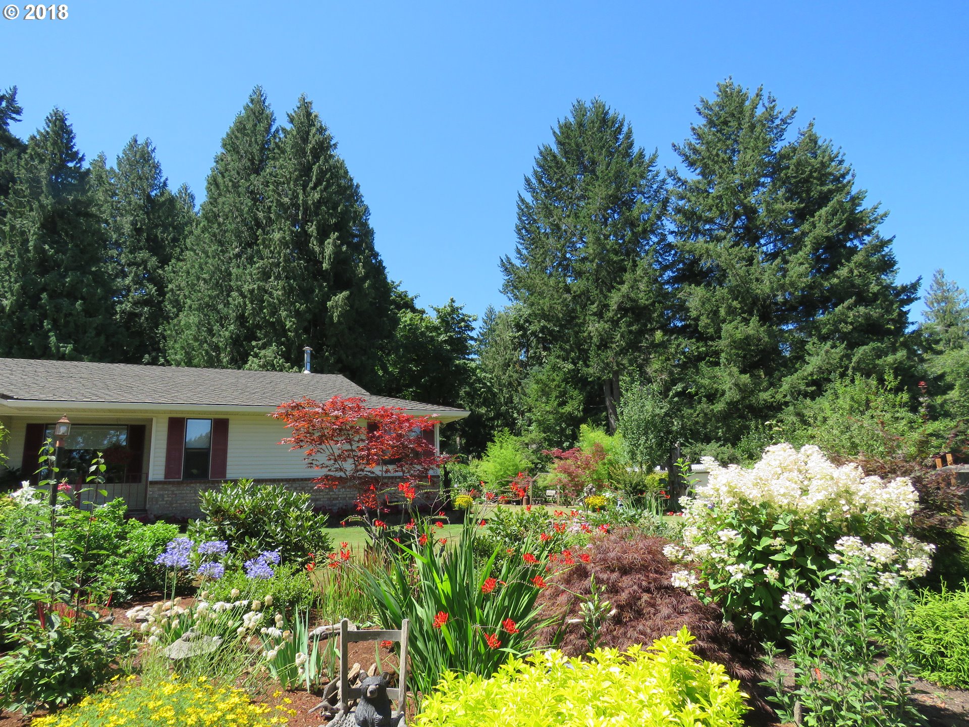 7635 Southeast Barbara Welch Road Portland, OR 97236 - Photo 25 of 26 a view of a house with a flower garden in front of it