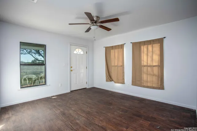 a view of an empty room with a window and wooden floor