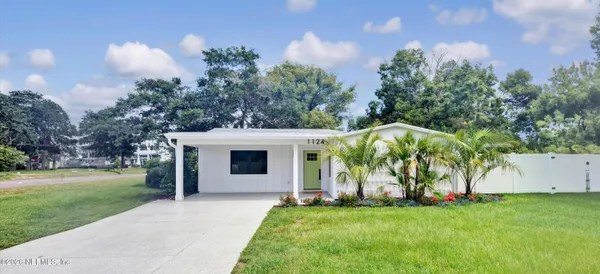 a view of a white house with a big yard and potted plants and trees