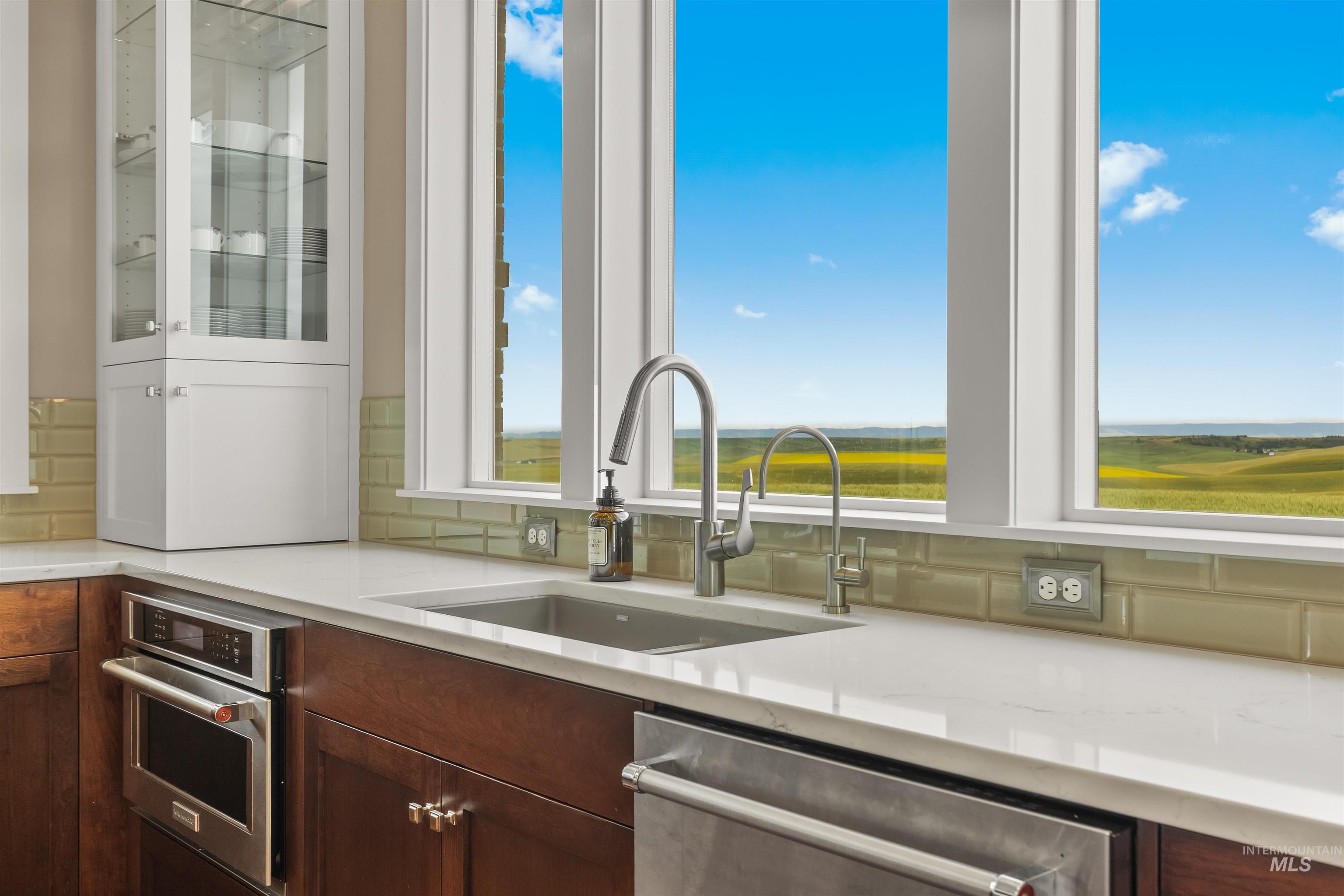 1513 Uniontown Road Genesee, ID 83832 - Photo 26 of 50 Double vanity with rectangular vessel sinks and brushed nickel faucets, featuring wood-finish cabinetry, a neutral countertop, and a tiled backsplash