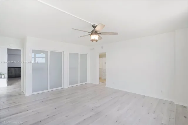 an empty room with wooden floor ceiling fan and window