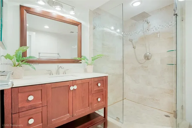 a bathroom with a granite countertop sink a mirror and a shower