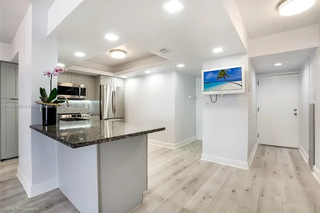a kitchen with stainless steel appliances granite countertop a sink and a refrigerator