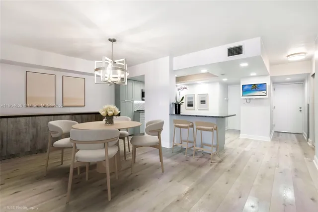 a dining room with wooden floor a chandelier a wooden table and chairs