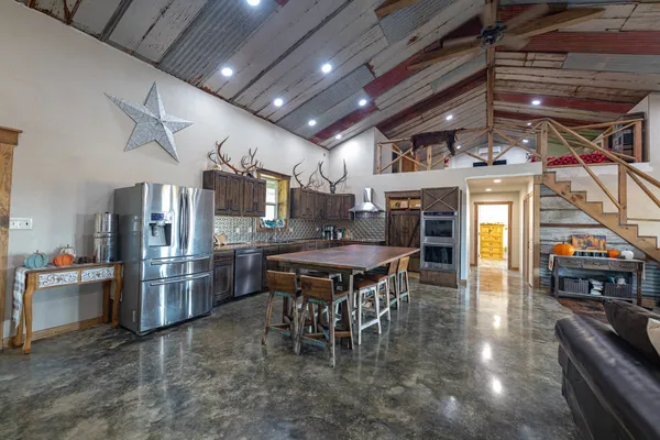 a kitchen with stainless steel appliances kitchen island granite countertop a table chairs and a refrigerator