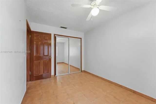 an empty room with closet and a chandelier fan