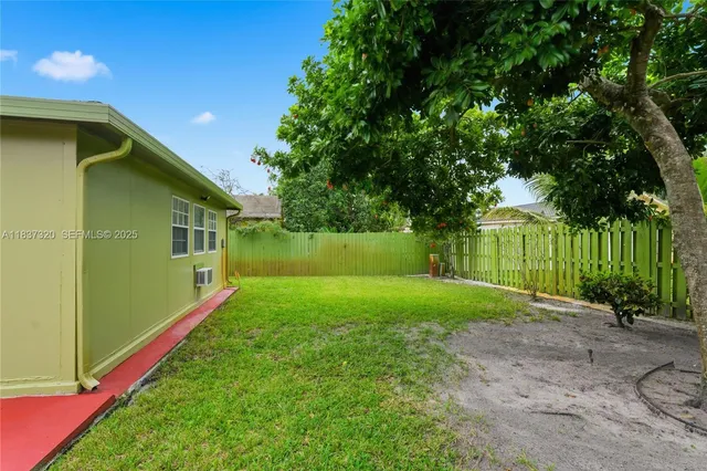a backyard of a house with plants and wooden fence