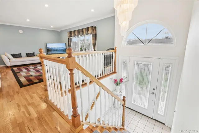 a view of a hallway with a large white bed wooden floor and staircase