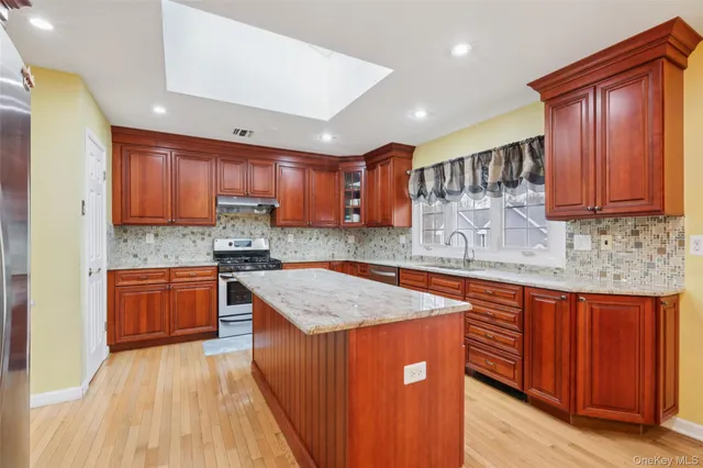 a kitchen with stainless steel appliances granite countertop wooden cabinets a sink and dishwasher a stove with wooden floors