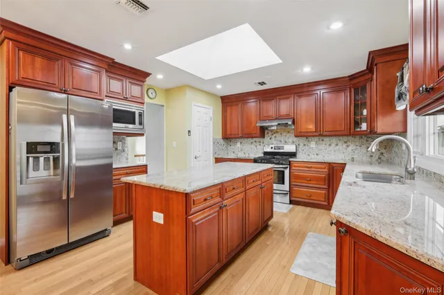 a kitchen with stainless steel appliances granite countertop a sink a stove and a refrigerator