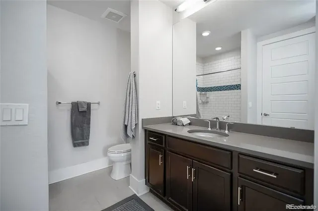 a bathroom with a granite countertop sink a large mirror and toilet