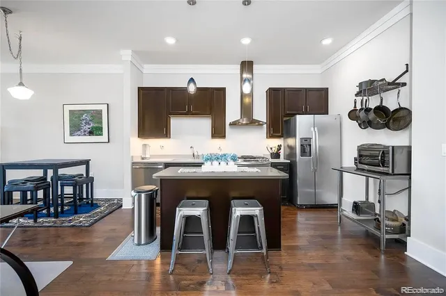 a kitchen with stainless steel appliances granite countertop a stove top oven a sink a dining table and chairs with wooden floor