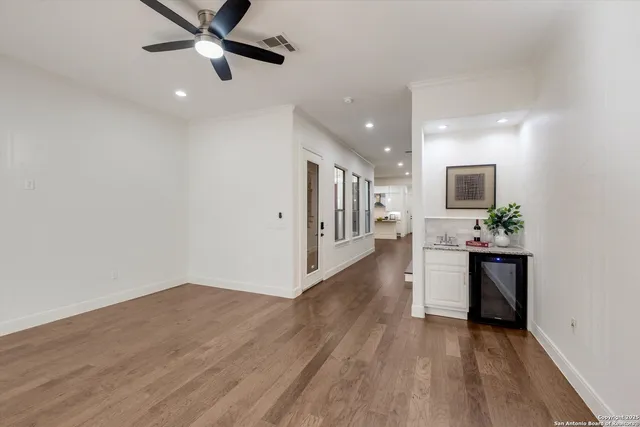 a view of a hallway with wooden floor and a bathroom