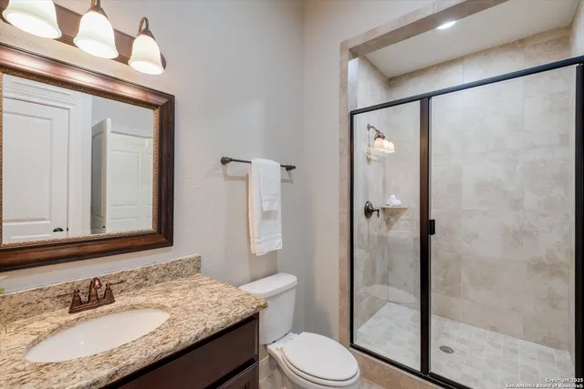 a bathroom with a granite countertop sink toilet mirror and shower