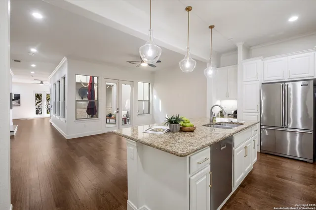 a kitchen with stainless steel appliances granite countertop a refrigerator a sink dishwasher a refrigerator white cabinets and wooden floor