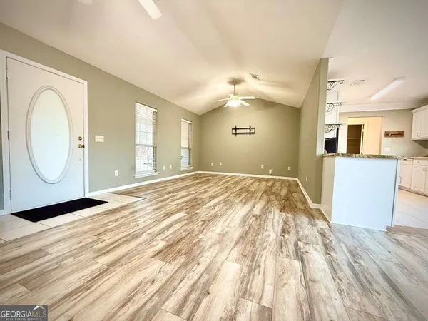 a view of an empty room with window and wooden floor