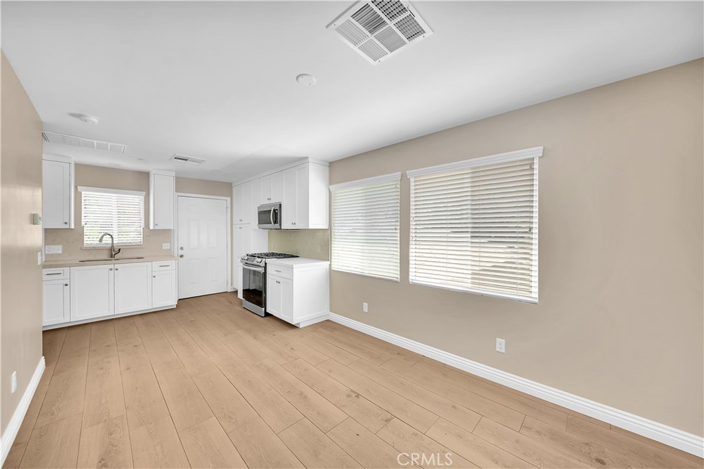 6735 B Yellowstone Drive Riverside, CA 92506 - Photo 4 of 15 a large white kitchen with white cabinets and wooden floors