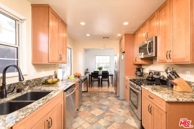 a kitchen with stainless steel appliances granite countertop a stove a sink and a microwave