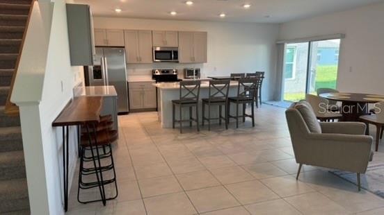 4520 Ranunculus Street Haines City, FL 33844 - Photo 3 of 19 a open kitchen with stainless steel appliances granite countertop a stove top oven a sink a dining table and chairs