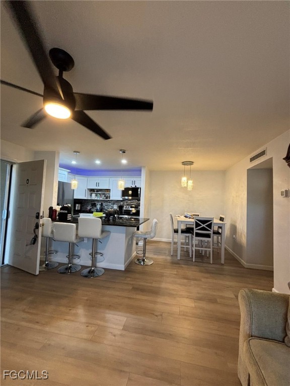 5713 Foxlake Drive, Unit 4 North Fort Myers, FL 33917 - Photo 3 of 13 a kitchen with stainless steel appliances kitchen island granite countertop a refrigerator a stove a dining table and chairs with wooden floor