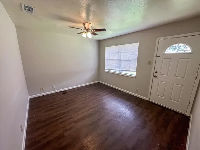 an empty room with wooden floor fan and windows