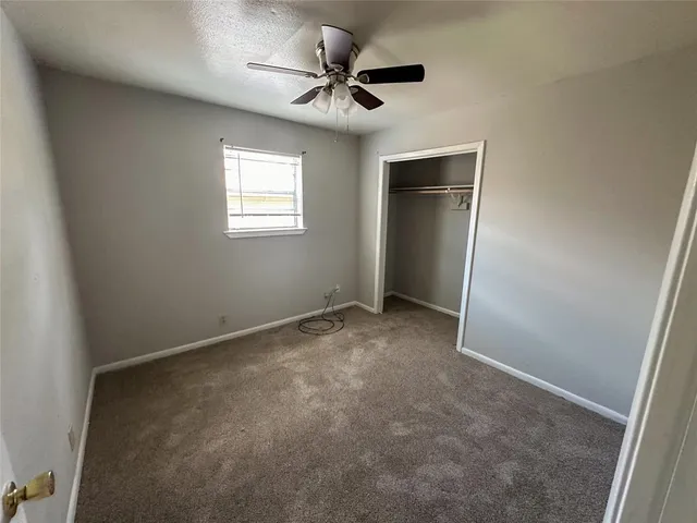an empty room with a ceiling fan and a window