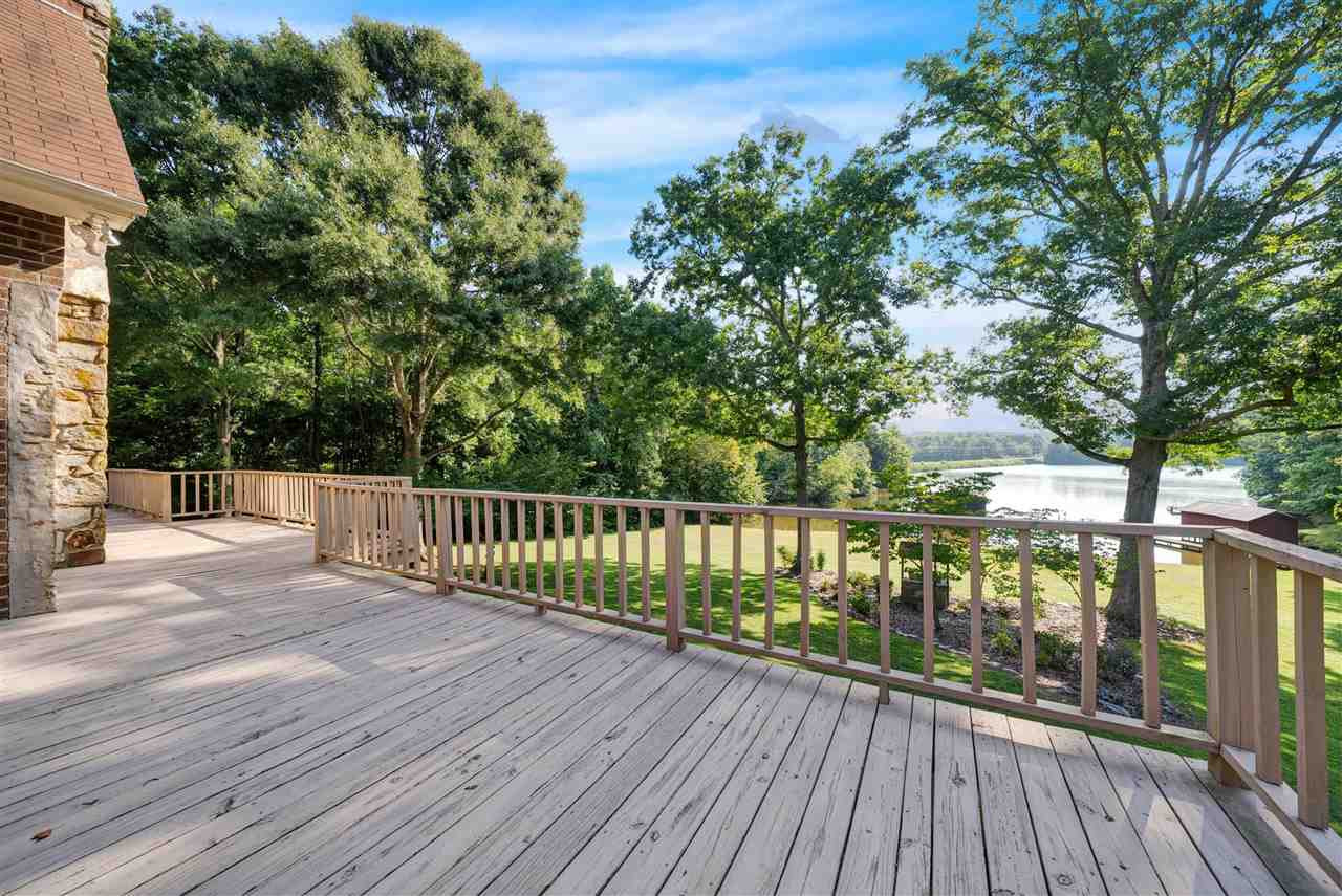 a view of deck with wooden floor and fence next to a yard