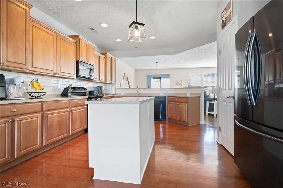 9188 Prairie Moon North Ridgeville, OH 44039 - Photo 20 of 40 Kitchen featuring backsplash, dark hardwood / wood-style flooring, black appliances, and kitchen peninsula