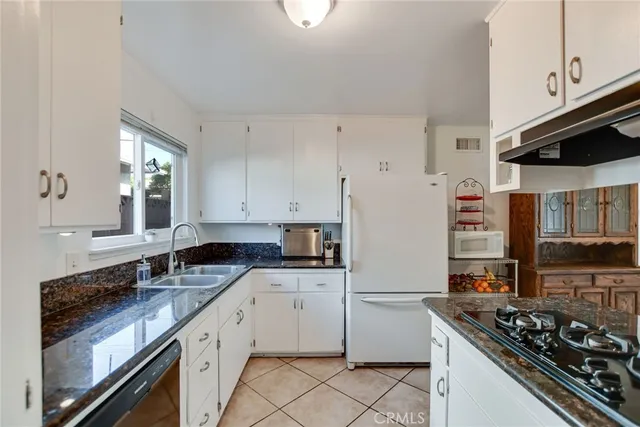 a kitchen with granite countertop white cabinets and white appliances